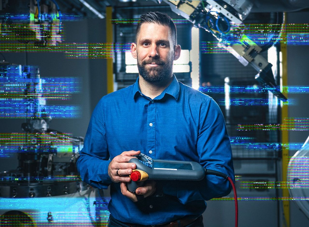Ein Mann hält ein technisches Gerät in einer industriellen Umgebung. Das Bild ist teilweise verpixelt.