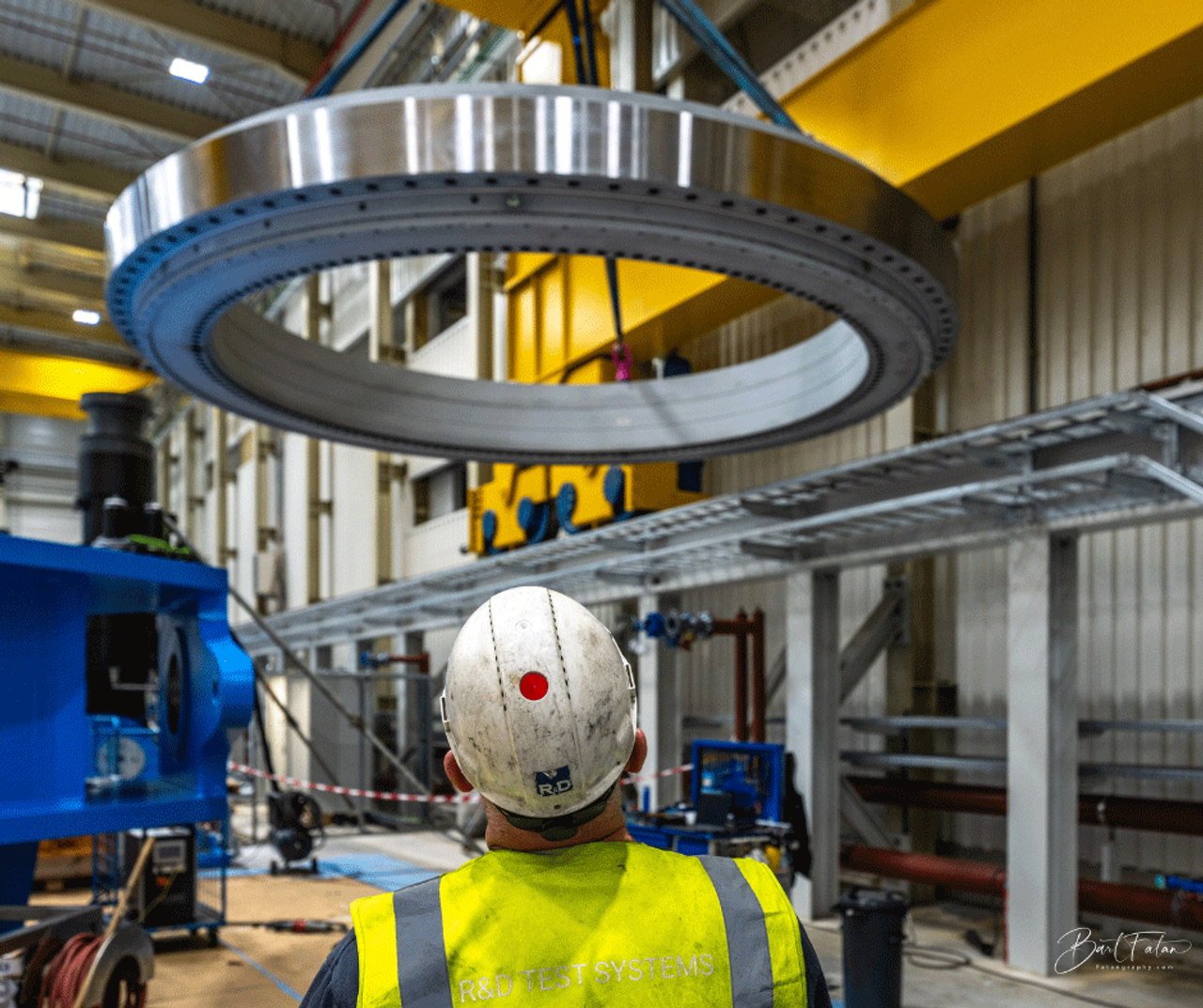 A man in protective clothing looks up at a slewing bearing